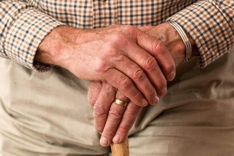 Hands of an older man on a cane