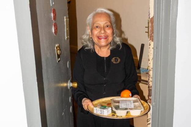 Smiling older woman receiving at-home meal service